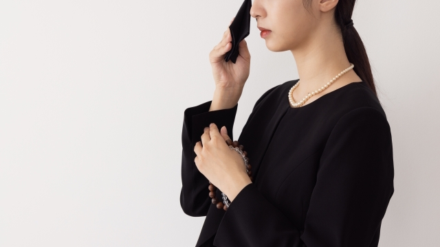 お葬式で泣いてハンカチで涙を拭いている女性