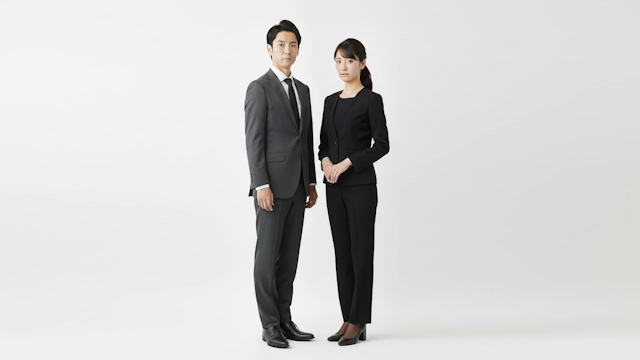 略喪服としてダークスーツを着ている男性と黒いパンツスーツを着ている女性