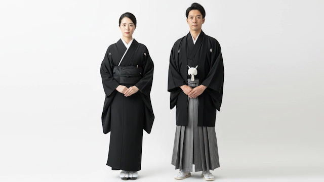 正喪服として五つ紋の黒無地の紋付羽織袴を着た男性と黒無地の紋付着物を着た女性