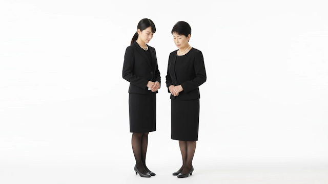 ヘチマ襟のジャケットの喪服を着た若い女性とノーカラーのジャケットの喪服を着た高齢の女性