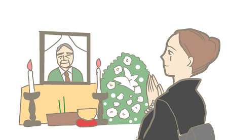 お葬式で手を合わせる喪服の女性